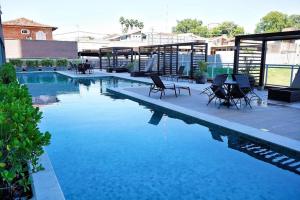 a swimming pool with chairs and a table next to it at Studio Prime Ribeirão Apogeo in Ribeirão Preto