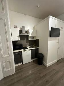 a small kitchen with white cabinets and a sink at Spacious Flat White City in London