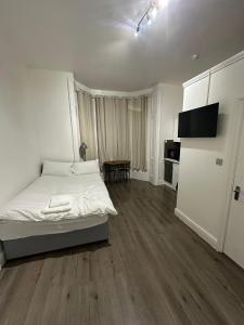 a white bedroom with a bed and a table at Spacious Flat White City in London