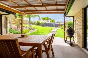 a patio with a wooden table and a grill at The Hideaway in Yeppoon