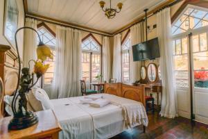 a bedroom with a bed and a desk and windows at Teatro Hotel Boutique in Ouro Preto
