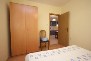 a bedroom with a bed and a chair and a kitchen at Apartments Zoki in Vis