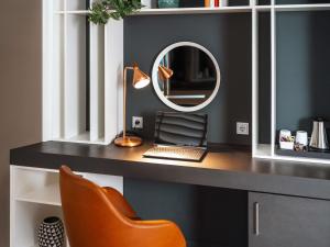 a desk with a laptop and a mirror at ibis Styles Neckarsulm in Neckarsulm