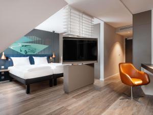 a bedroom with a bed and a flat screen tv at ibis Styles Neckarsulm in Neckarsulm +97 photos