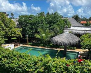 a swimming pool with an umbrella and some bushes at Atins - Vila Mani com piscina in Atins