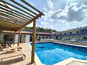 a pool at a hotel with chairs and a pergola at Hotel e Restaurante Star New in Carmópolis