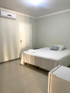 a white bedroom with a bed and a window at Hotel e Restaurante Star New in Carmópolis