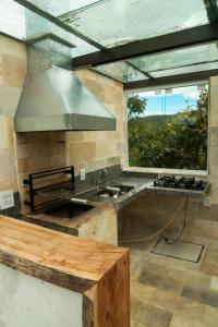 a kitchen with a sink and a large window at Casa junto as montanhas in Capitólio