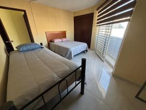 a bedroom with two beds and a large window at Depa Balbuena in Guadalajara