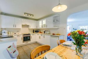 a kitchen with white cabinets and a wooden table at 3 Bed in Porthleven oc-1seav in Porthleven +11 photos