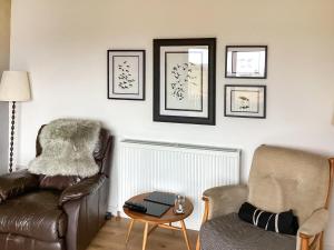 a living room with a leather couch and a chair at At Last in Rhiconich
