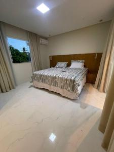 a bedroom with a bed and a large window at Casa Itacimirim in Camacari