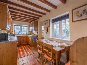 a kitchen with a wooden table and chairs and a kitchen withwindows at 3 Bed in Syderstone oc-kt083 in Syderstone
