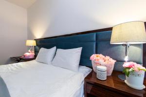 a bedroom with a bed with a blue headboard and flowers at Sunrise Garden Hotel 3* in Gagra