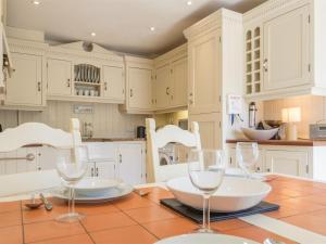 a kitchen with white cabinets and a table with wine glasses at 2 Bed in Dersingham oc-kt082 in Dersingham