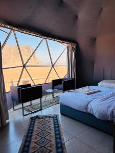 a bedroom with a bed and a large window at Rina Luxury Camp in Wadi Rum