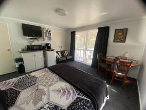 a bedroom with a bed and a table and a kitchen at Union Street Hideaway in Waihi
