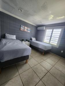 a bedroom with two beds and two windows at Ola Azul Apartment in Punta Santiago
