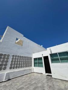 a white building with green windows and a door at Casa Toreo in Mazatlán