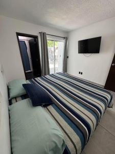 a large bed in a bedroom with a television on the wall at Casa Toreo in Mazatlán