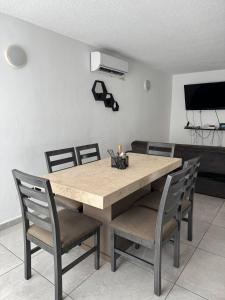 a dining room table with chairs and a television at Casa Toreo in Mazatlán