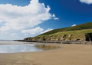 a beach with a grassy hill next to the ocean at 43 sea valley in Bideford