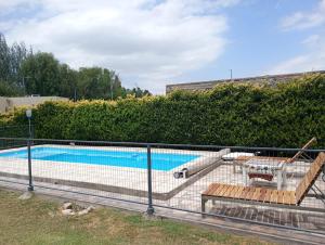 a swimming pool with two benches next to a fence at Quinta El Medanito in Trinidad