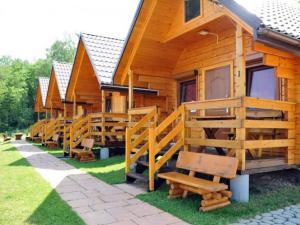 a row of wooden lodges with benches in the grass at Domki PIĘKNY WIDOK górne - Solina Centrum in Solina
