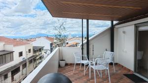 a balcony with chairs and a table with a view at Apart Hotel IQON Centro Histórico in Cuenca