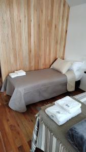 two beds in a room with wooden walls and wood floors at Refugios de Rio Ilo in Concepción del Uruguay