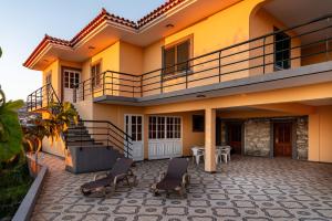 a house with two chairs and a balcony at Sunset House in Calheta