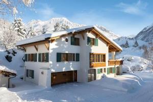 a house in the snow with mountains in the background at Chalet Gutsch Andermatt in Andermatt