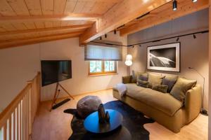 a living room with a couch and a tv at Chalet Gutsch Andermatt in Andermatt