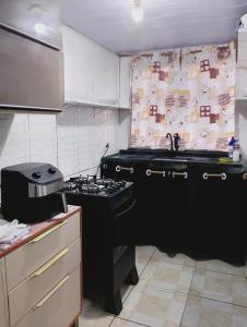 a kitchen with a black stove and a sink at casa 1 perto do pavilhão de Carapina a 8 kilometros do aeroporto in Serra