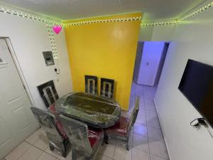 a room with a table and chairs and a yellow wall at casa renta vacacional en mazatlan in Mazatlán