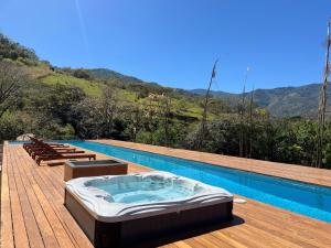 a swimming pool with a hot tub on a wooden deck at BEE Suites Santa Ana - San Jose in San José