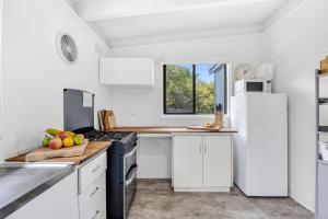 a kitchen with white cabinets and a stove top oven at Oceanside Escape in Aireys Inlet +3 photos