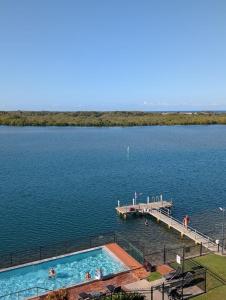 a swimming pool on a lake with a dock at Banyandah Towers in Maroochydore