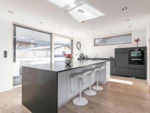 a kitchen with a black and white counter and stools at Alpin Chalet ARTE in Söll