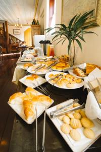a long table filled with plates of bread and pastries at Teatro Hotel Boutique in Ouro Preto