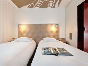 a bedroom with two beds with a book on them at ibis Styles Lille Aéroport in Lesquin +92 photos