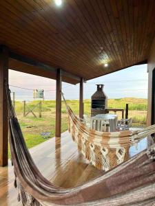 a hammock on a porch with a view of a field at Chalé Horizonte do Silva in Arroio do Silva