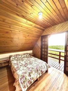 a bedroom with a bed in a wooden cabin at Chalé Horizonte do Silva in Arroio do Silva
