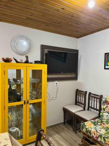 a living room with a yellow cabinet and a flat screen tv at Chalé Horizonte do Silva in Arroio do Silva