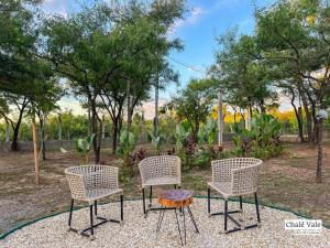 three chairs and a table in a park at Chalés Exclusivos com Jacuzzi em Bonito Mato Grosso do Sul in Bonito