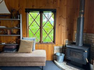 a room with a stove and a couch and a window at Cygnet Cabin in Lymington