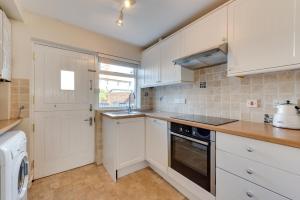 a kitchen with white cabinets and a stove top oven at 4 Bed in Southwold oc-ivy in Southwold +3 photos