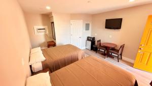 a hotel room with two beds and a table and a television at Beachtree Motel in Galveston +13 photos