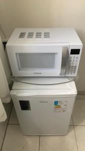 a microwave oven sitting on top of two servers at Kitnet Equipada in Sao Jose do Rio Preto