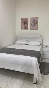 a white bed with two pictures on the wall at Kitnet Equipada in Sao Jose do Rio Preto